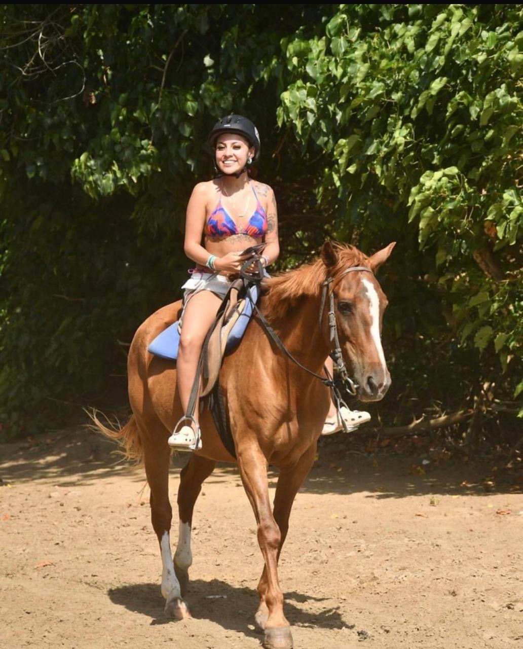 Smiling guest on horseback on a shady trail