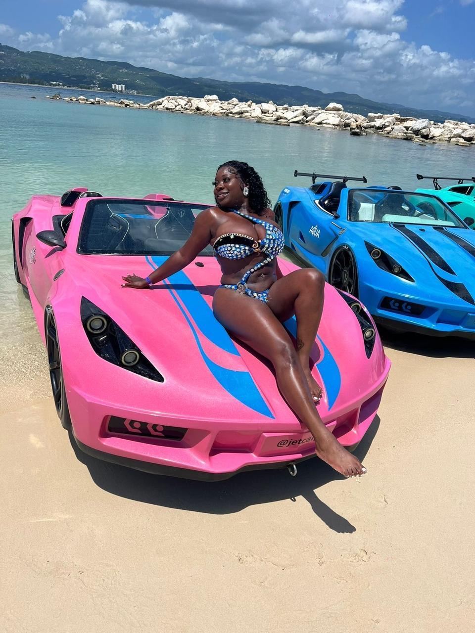 Guest posing on a pink jet car